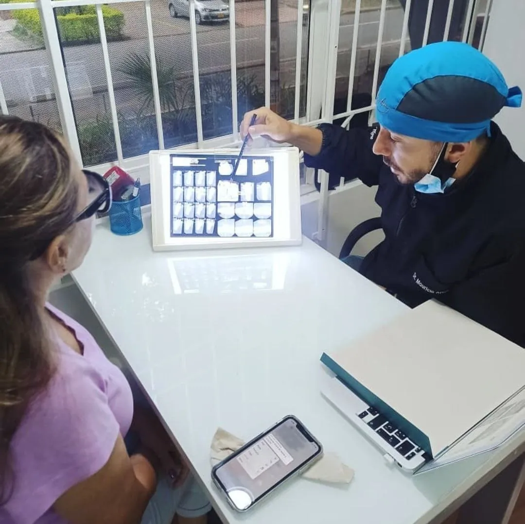 Odontólogo revisando radiografías con una paciente en Medellín